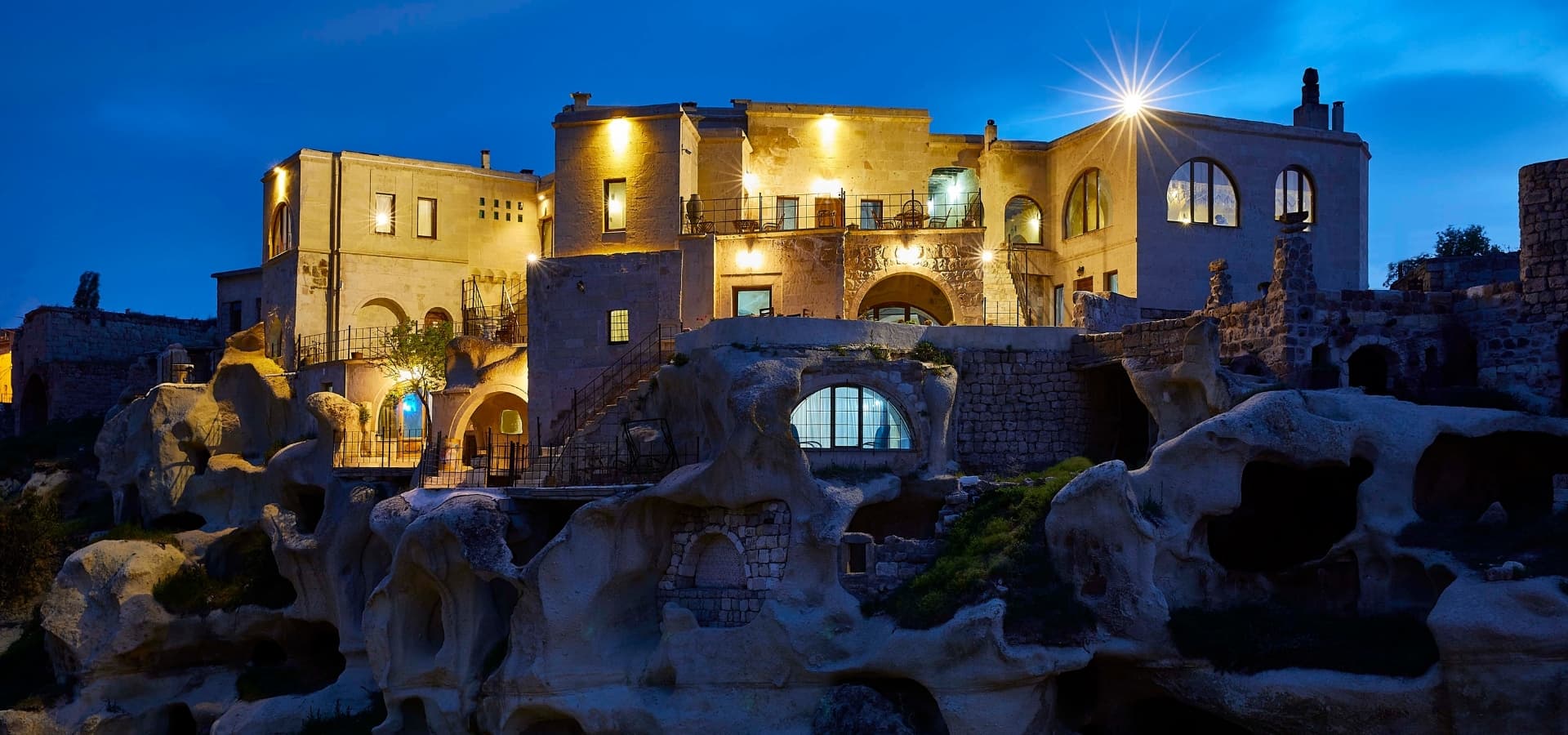 Charm of Cappadocia'nın alacakaranlıkta kayaya oyulmuş taş cephesi
